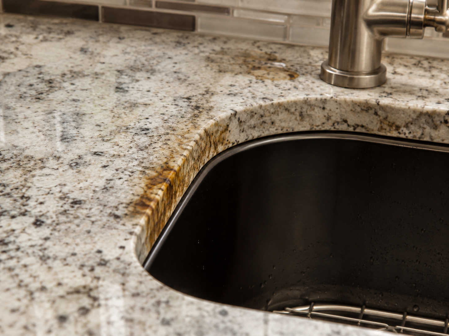 Water and residue staining around a granite kitchen sink