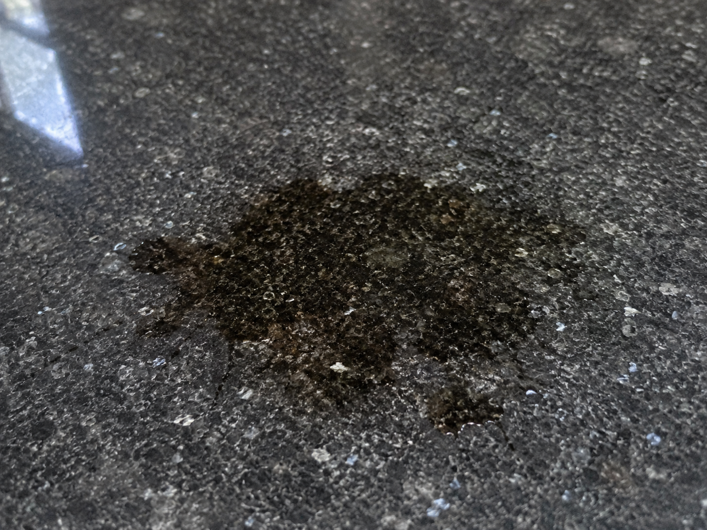 Large dark stain visible on a light granite kitchen countertop