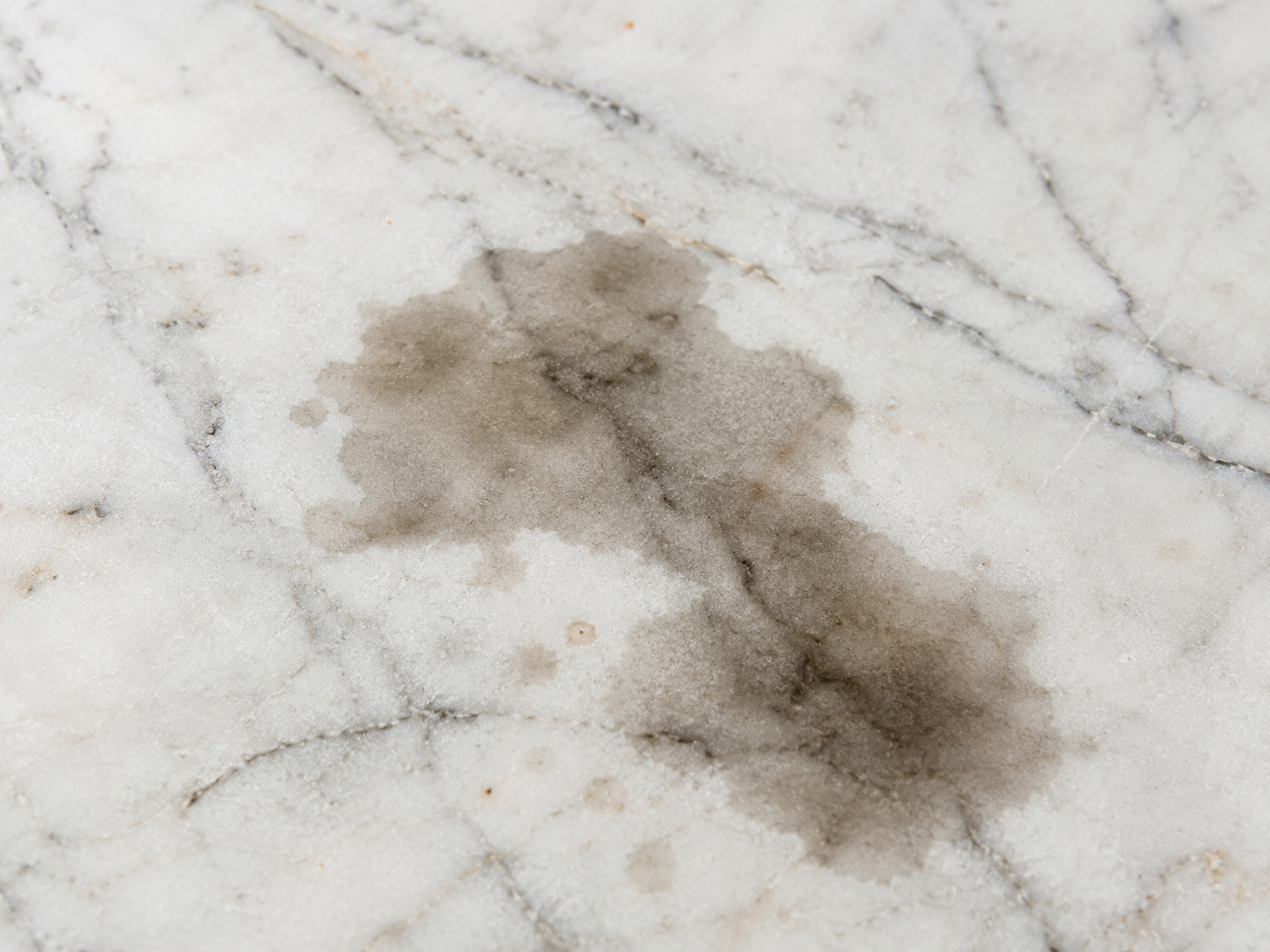 Oil and grease stain visible on a white marble kitchen countertop